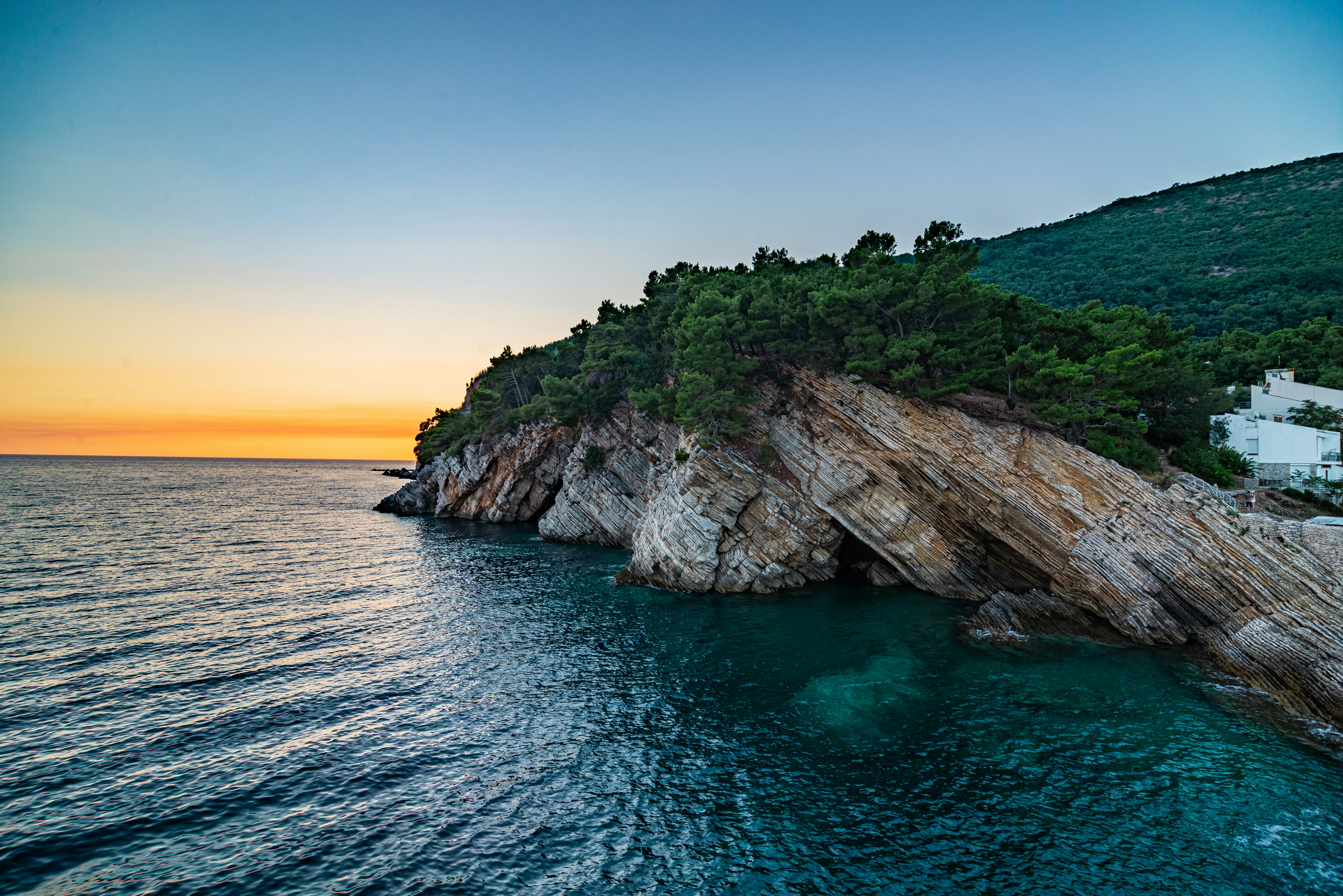 brown and green rock formation on blue sea under blue sky during daytime